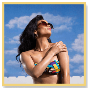 a woman in a bikini and sunglasses applies baby oil
